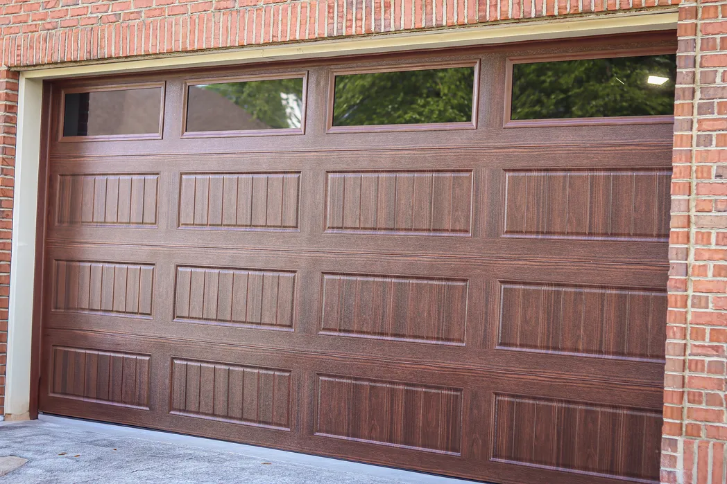 Carriage house garage door with decorative overlays and windows
